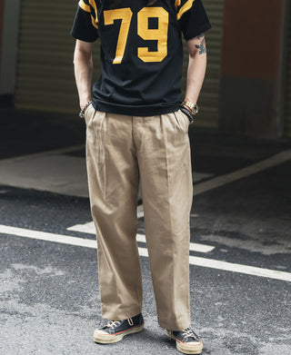 Khaki chino pants on model, straight legs with pleated front and cuffed hem