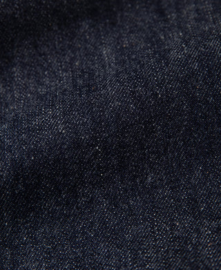 Dark indigo denim fabric close-up with visible weave texture and stitching