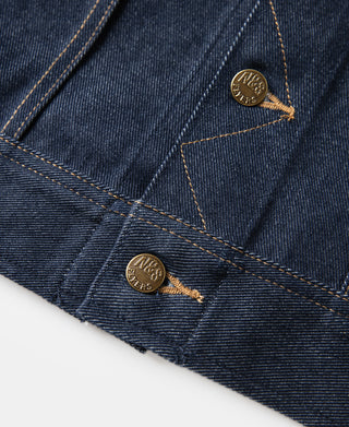 Indigo denim jacket pocket flap with gold-tone rivets and contrast tan stitching
