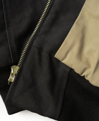 Black bomber jacket sleeve cuff with gold zipper pull and ribbed knit trim