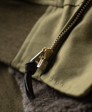 Khaki flight jacket front zipper and metal pull with leather cord detail