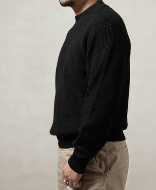 Black wool crewneck sweater worn on model, side profile with ribbed cuffs