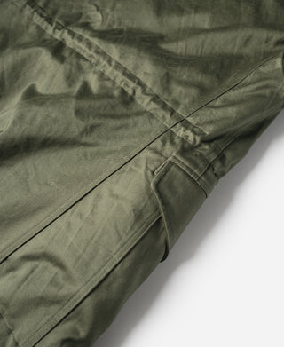 Olive field jacket side panel with stitched seams and flap detail, angled close-up