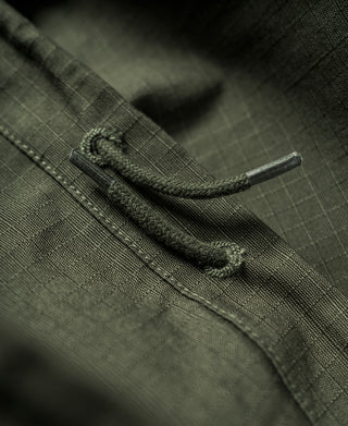Olive fatigue pants with drawstring cuff and cord stopper, close-up