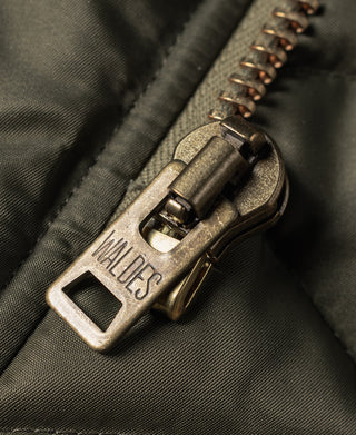 Olive N-3 parka zipper with metal pull and engraved brand tag.