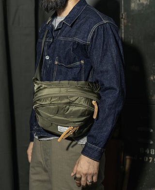 Olive waist bag worn on a person over a denim jacket, side view