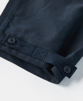 Navy deck pants hem band close-up with button, pleat detail, and seam stitching