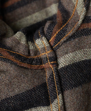 Indigo denim jacket front seam with plaid blanket lining at collar opening