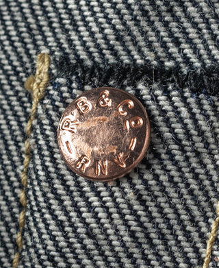 Indigo selvedge denim jeans, copper-toned button detail on dark denim texture