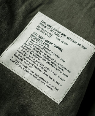 Olive fatigue jacket inside care label with instructions and fabric details