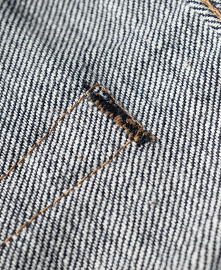 Selvedge denim edge detail with white-and-blue warp stripes and orange-brown thread