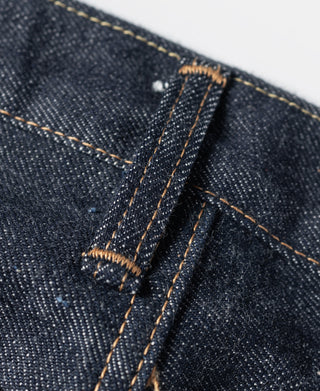 Indigo denim button fly area with bar-tack reinforcement and orange stitching