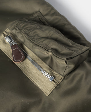 Olive N-3 parka interior pocket with metal zipper and brown leather pull tab.