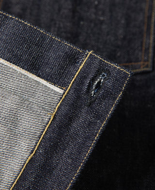 Indigo denim jacket pocket opening with inner fabric lining and gold topstitching.