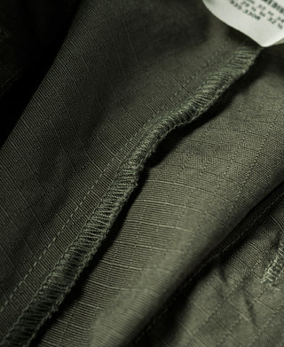 Olive fatigue pants cuff with reinforced seam stitching, close-up