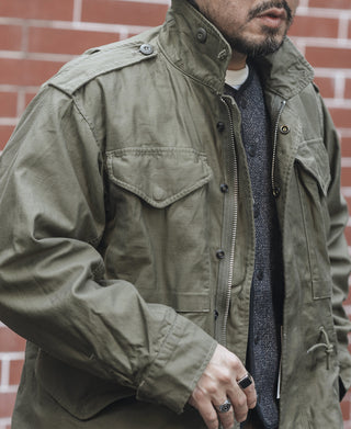 Olive field jacket with zip front, snap button pockets, drawstring hem