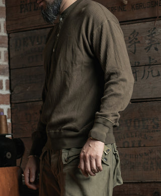 Man wearing an olive-brown ribbed long-sleeve henley shirt with three-button front