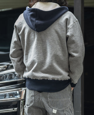 Two-tone hooded sweatshirt, gray back with navy hood, ribbed hem, worn with striped pants