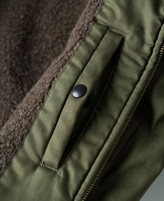 Olive flight jacket inner tab with snap button near zipper placket