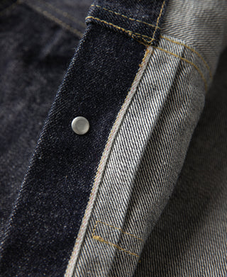 Indigo denim jacket placket with round snap button and contrast seam lines.