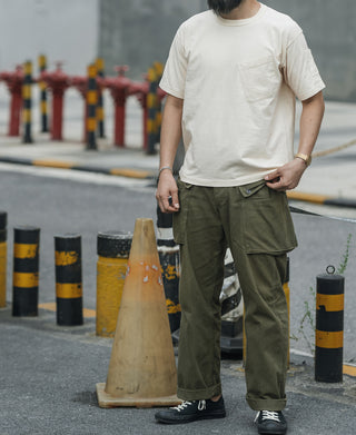 Olive utility cargo pants worn with cuffed hems and multiple side pockets