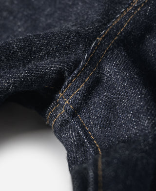 Indigo selvedge denim jeans—close-up of fabric fold with orange-brown stitch lines