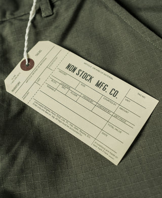 Olive fatigue pants with attached hang tag, close-up