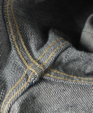 Indigo selvedge denim jacket close-up: gold topstitching at placket and collar