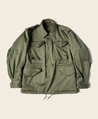Olive field jacket with snap front, flap chest pockets, and drawstring hem
