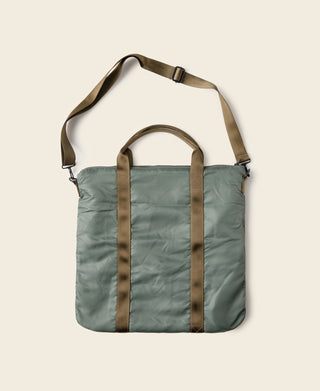 Sage green padded helmet bag with brown leather-look straps and top carry handle