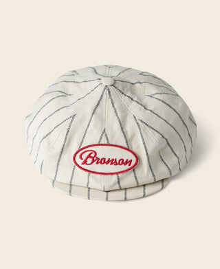 White newsboy cap with blue pinstripes and Bronson logo patch on crown