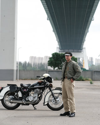 Olive MA-1 flight jacket on model standing outdoors, front zipper and ribbed cuffs visible