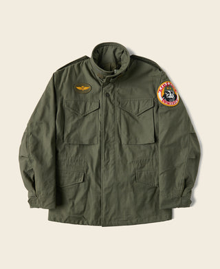 Olive field jacket with front zipper, hood, chest pockets, and embroidered patch