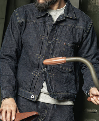 Indigo denim jacket with button front and flap chest pockets, worn with gray shirt