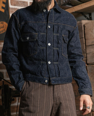 Indigo denim jacket with button-front, flap chest pockets, and pleated back yoke