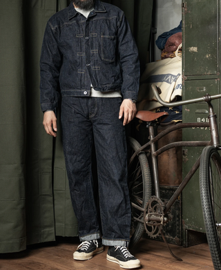 Dark indigo denim jeans worn with sneakers, full-body front view