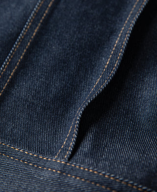 Indigo denim jacket seam with orange-brown contrast topstitching detail
