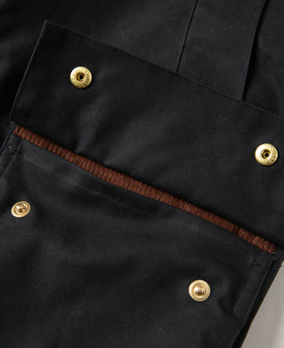 Black waxed chore jacket front with brass snaps and brown inner trim