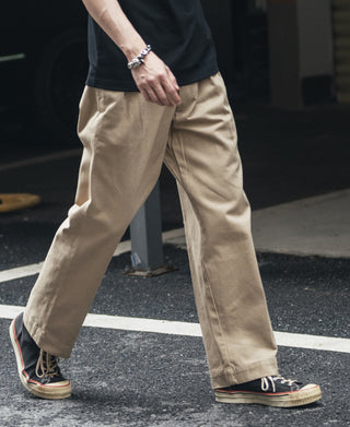 Khaki chino pants on model, full length with crease and cuffed bottoms