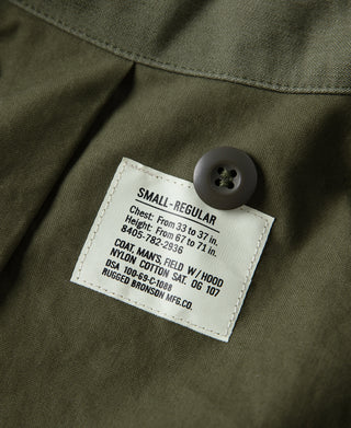 Olive field jacket size label with dark button on fabric panel