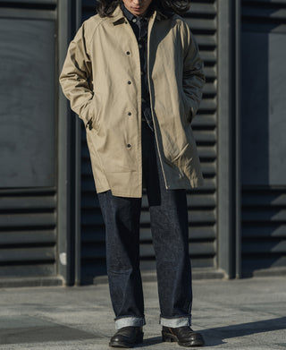 Khaki all-weather trench coat on model, button-front and dark shirt underneath