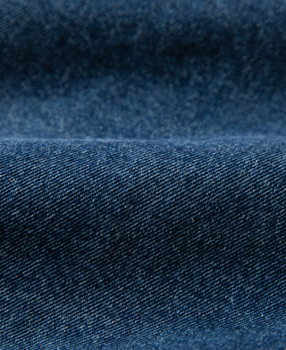 Stonewashed indigo denim fabric close-up with speckled texture