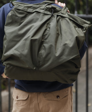 Olive nylon helmet bag with side pockets, straps, and black hardware