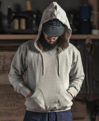 Gray terry hooded sweatshirt with drawstring hood; front view over dark pants