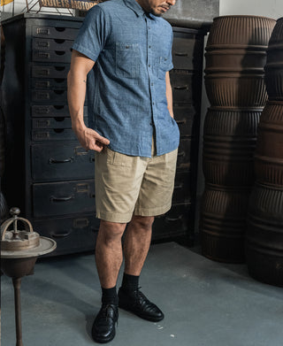 Blue chambray short-sleeve button-up work shirt with pointed collar and chest pockets.