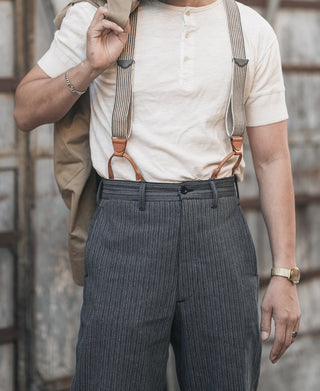 Waistband detail of dark striped pants with belt loops and metal button