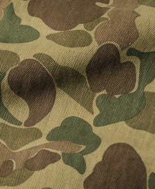 Camouflage cotton pants fabric close-up with herringbone texture in olive, tan, and brown.