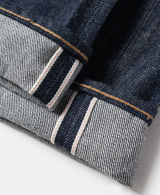 Denim jeans cuff with contrast tan-orange topstitching and off-white inner tape
