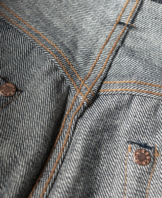 Dark denim jeans waist and fly area with tan stitching and metal button
