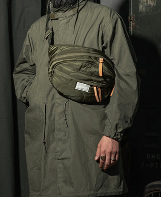 Olive green waist bag with textured quilted front panel and orange zipper pull